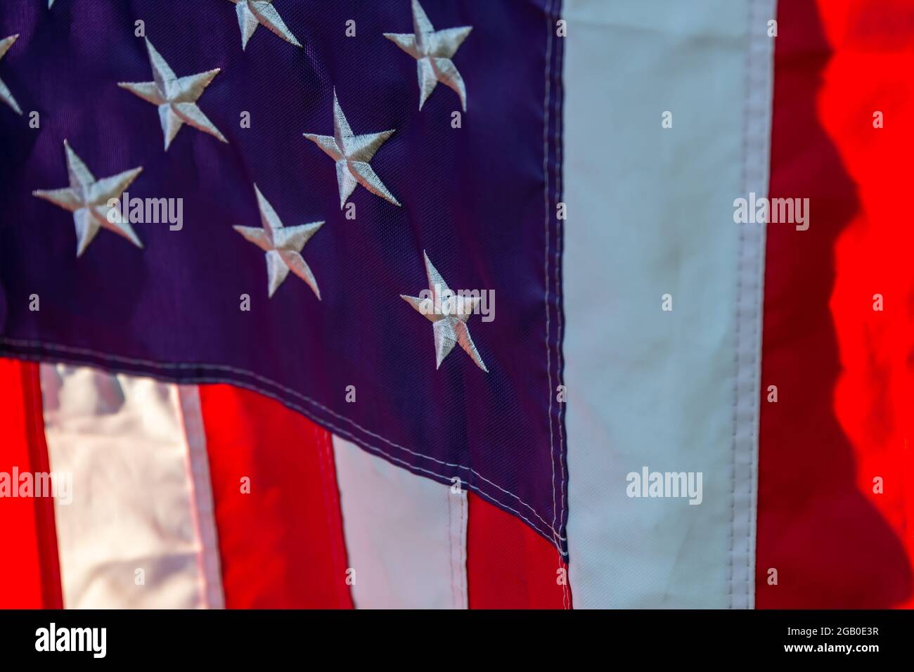 Teilansicht des Sternenfeldes und einige Streifen einer amerikanischen Flagge, die am 4. Juli vor einem Haus hängt. Stockfoto