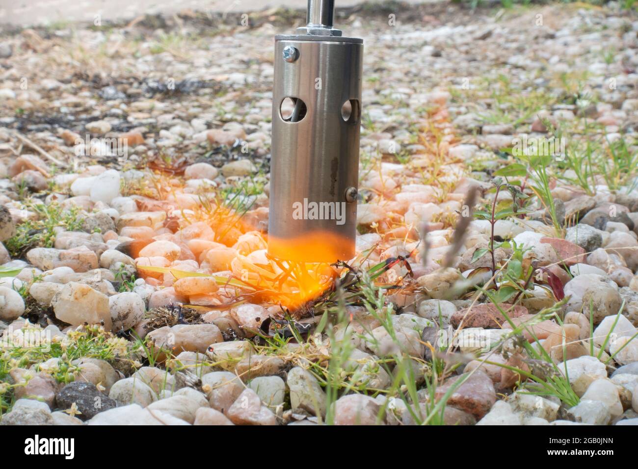 Verwenden eines Flammenbrenners, um Unkraut auf einem Kiesweg zu verbrennen Stockfoto