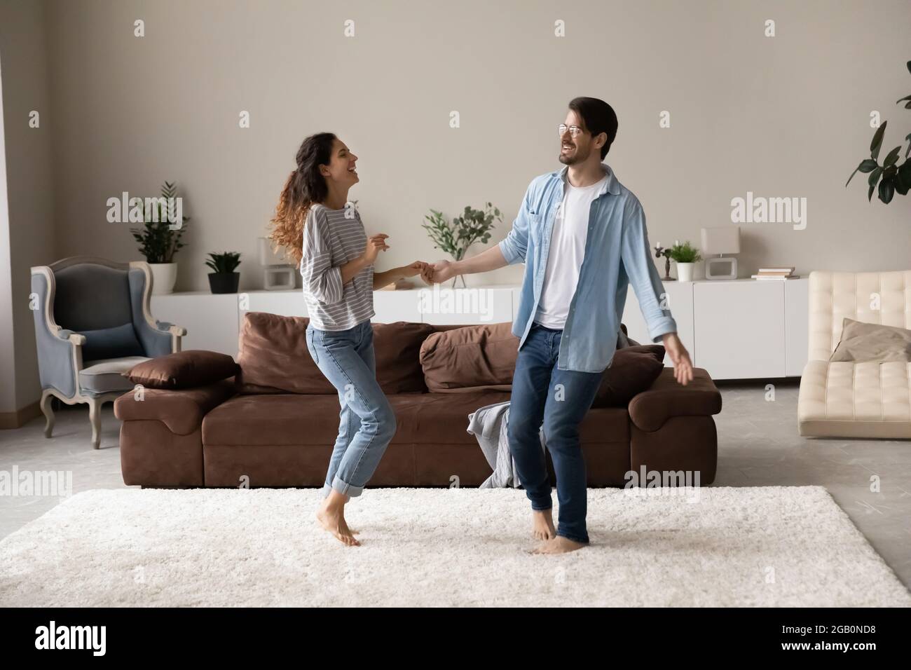 Glücklich aufgeregt Millennial Paar tanzen zusammen im Wohnzimmer Stockfoto