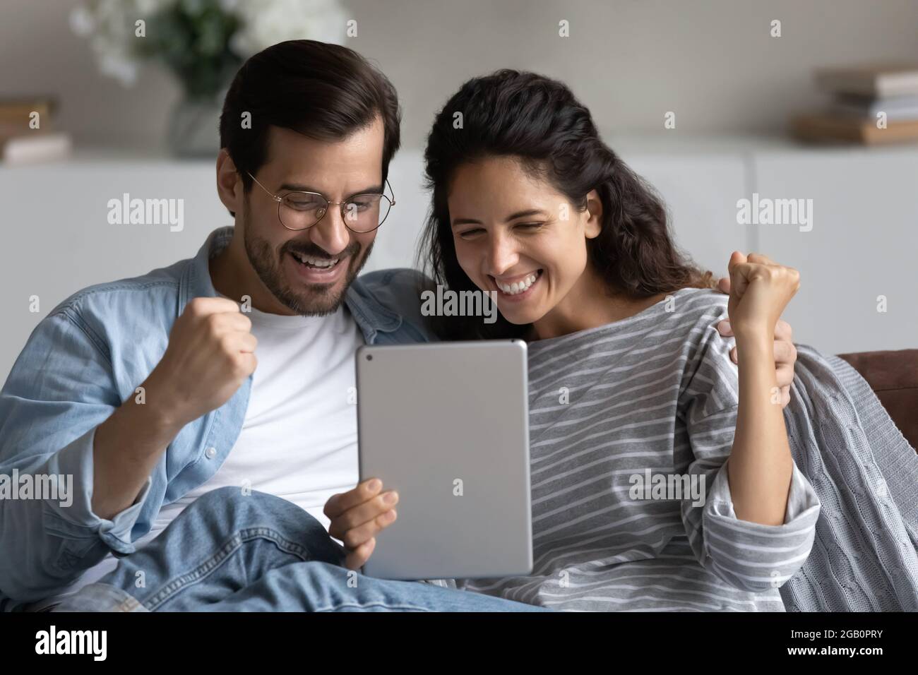 Glücklich aufgeregt 30er Jahre Paar mit Tablet zu Hause Stockfoto