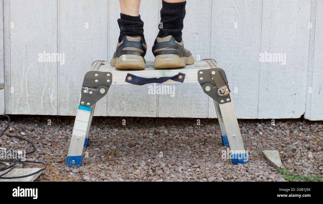 Die Füße einer Person stehen auf einem Stehhocker Stockfoto