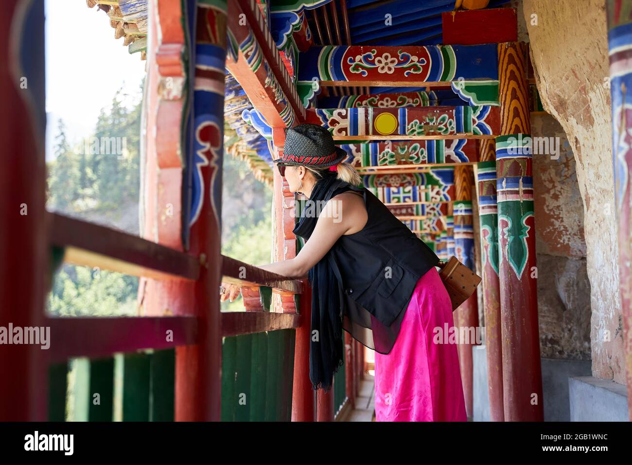asiatische Frau, die von innen aus eine alte tibetische religiöse Architektur betrachtet Stockfoto