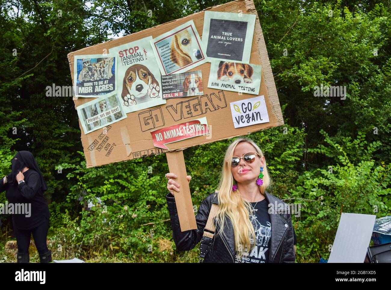 Huntingdon, Großbritannien. August 2021. Ein Demonstrator hält während der MBR Acres-Proteste in Huntingdon, Cambridgeshire, ein Anti-Tierversuchsschild und ein pro-veganes Plakat. Tierschutzaktivisten versammelten sich vor dem Beagle-Brutplatz von MBR Acres, um die Freilassung von 2000 Beagles zu fordern, von denen die Demonstranten behaupten, dass sie für grausame Experimente aufgezogen werden. Dutzende von Aktivisten haben auch außerhalb des Geländes ein langfristiges Camping eingerichtet, um das Unternehmen unter Druck zu setzen, die Hunde freizulassen und die Anlagen zu schließen. (Foto: Vuk Valcic/SOPA Images/Sipa USA) Quelle: SIPA USA/Alamy Live News Stockfoto