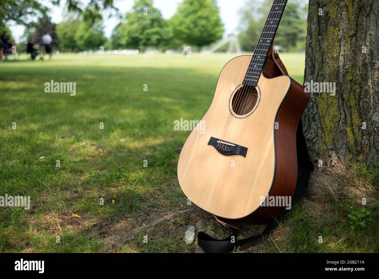 Klassische Gitarre lehnt sich an einen Baum in einem Park Stockfoto