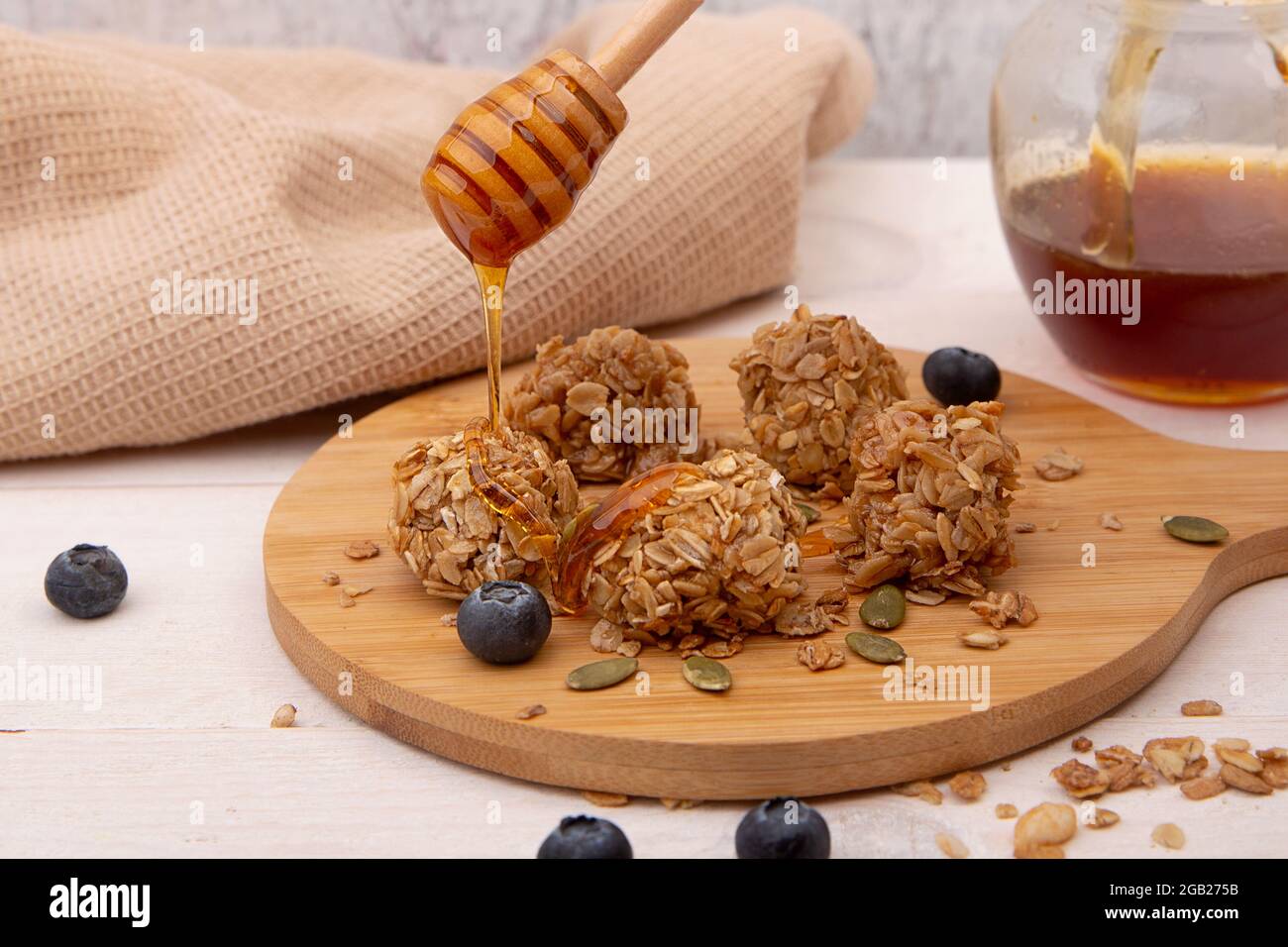 Energy Granola beißt mit Honig auf einem Holzteller/ Stockfoto