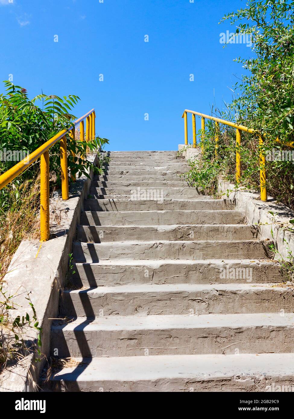 Architektonische Elemente der alten Betontreppe mit gelbem Geländer nach oben Stockfoto