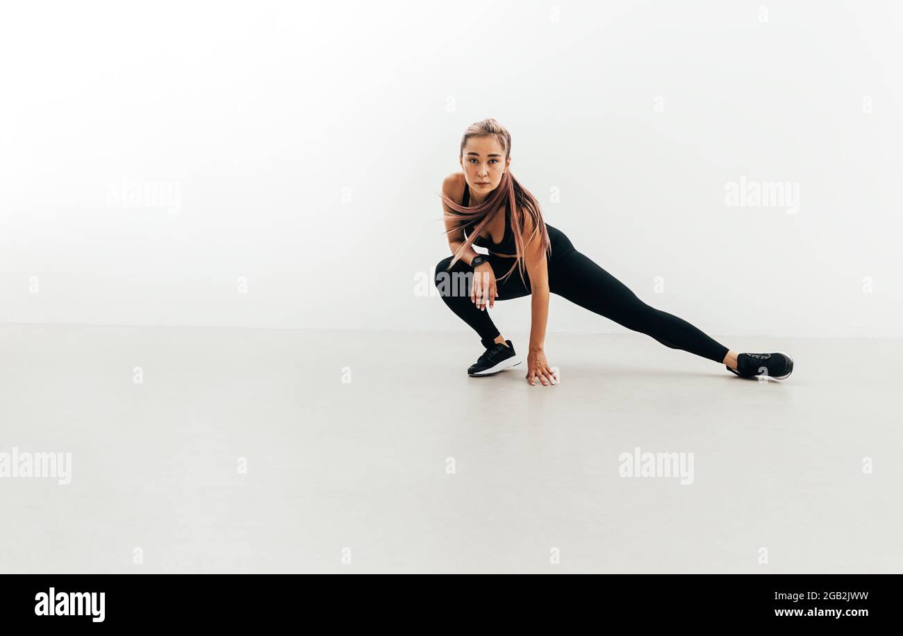 Sportlerin macht Dehnübungen in Innenräumen vor dem Training Stockfoto