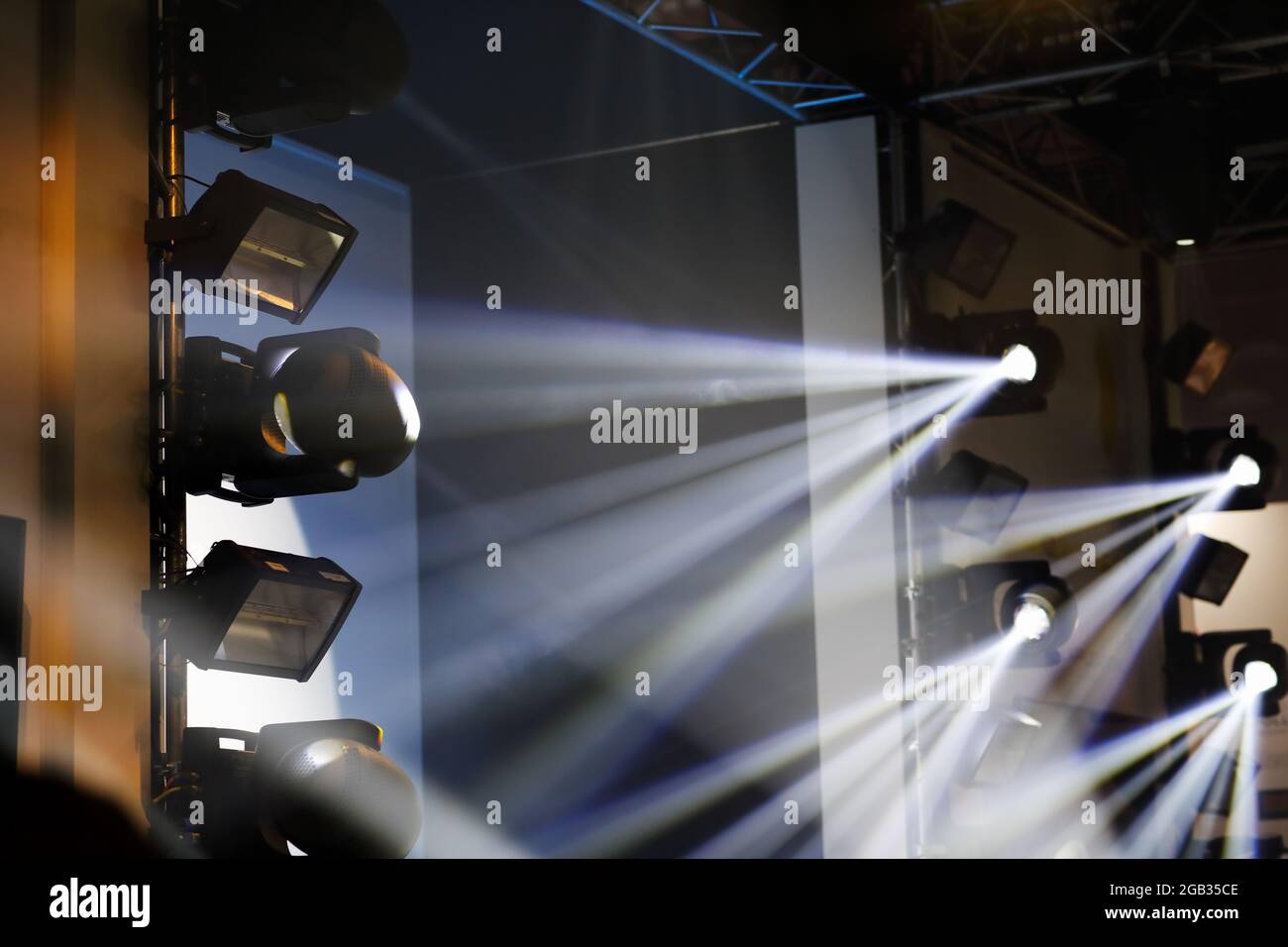 Bühnenbeleuchtung. Erkennen Sie sich bewegende Köpfe mit hellen weißen Lichtstrahlen. Selektiver Fokus. Stockfoto