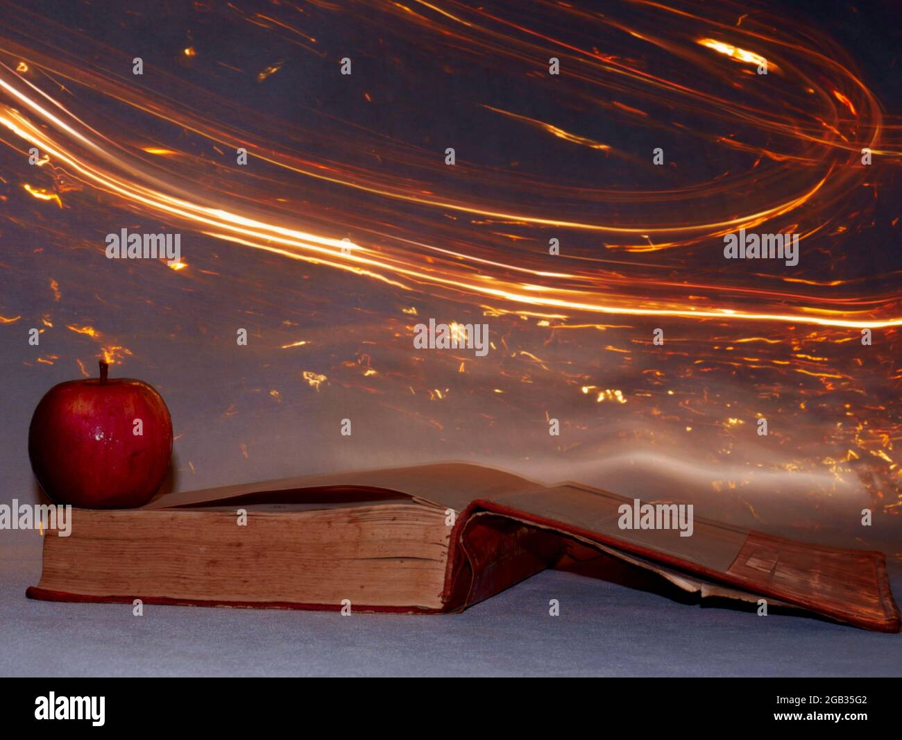 Apfel mit Buchpräsentation auf Feuerlicht-Hintergrund-Effekt. Stockfoto