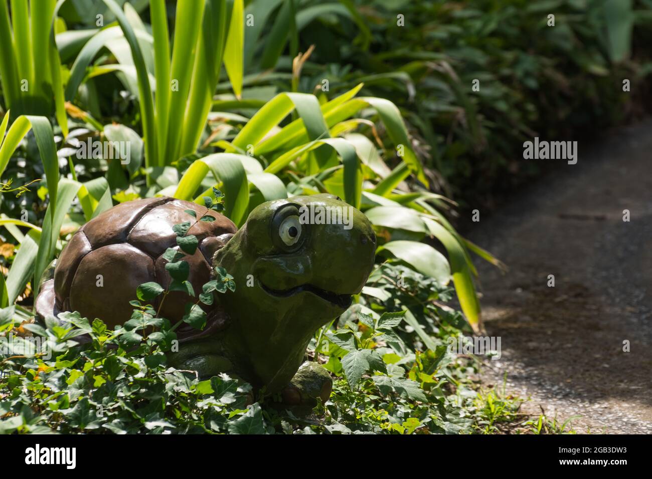 Lächelnde Schildkröte zwischen grünen Pflanzen in einem Minigolfplatz aus einem Vergnügungspark im Urlaub Stockfoto
