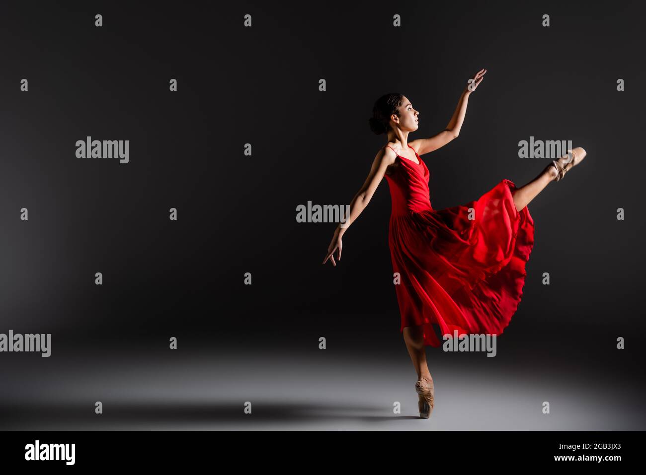 Seitenansicht der Ballerina, die ein Bein auf schwarzem Hintergrund tanzt Stockfoto