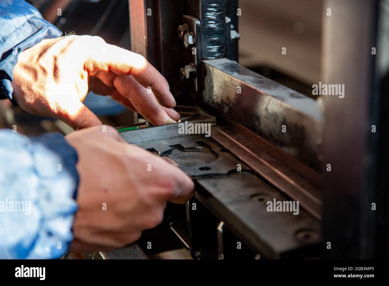 Ein Handwerker, der ein Stück Stahl für die Herstellung biegt Stockfoto