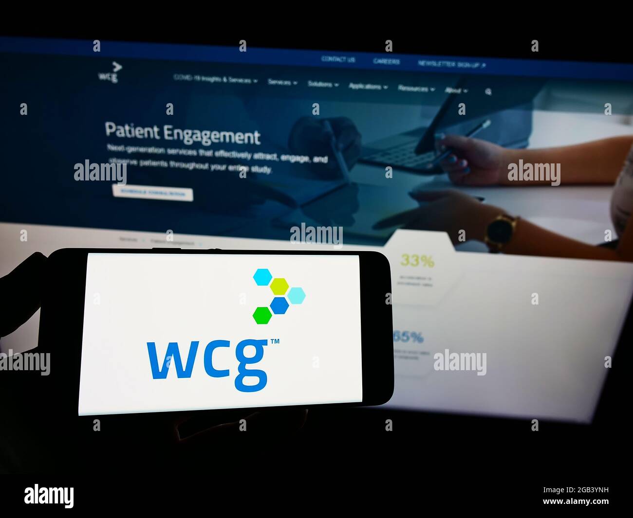 Person mit Mobiltelefon und Logo der Firma WIRB-Copernicus Group Inc. (WCG Clinical) auf dem Bildschirm vor der Webseite. Konzentrieren Sie sich auf die Telefonanzeige. Stockfoto