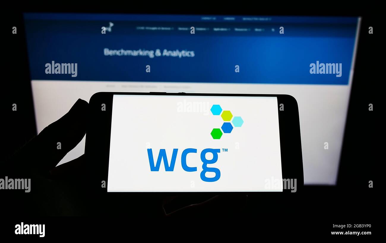 Person mit Mobiltelefon und Logo der Firma WIRB-Copernicus Group Inc. (WCG Clinical) auf dem Bildschirm vor der Webseite. Konzentrieren Sie sich auf die Telefonanzeige. Stockfoto