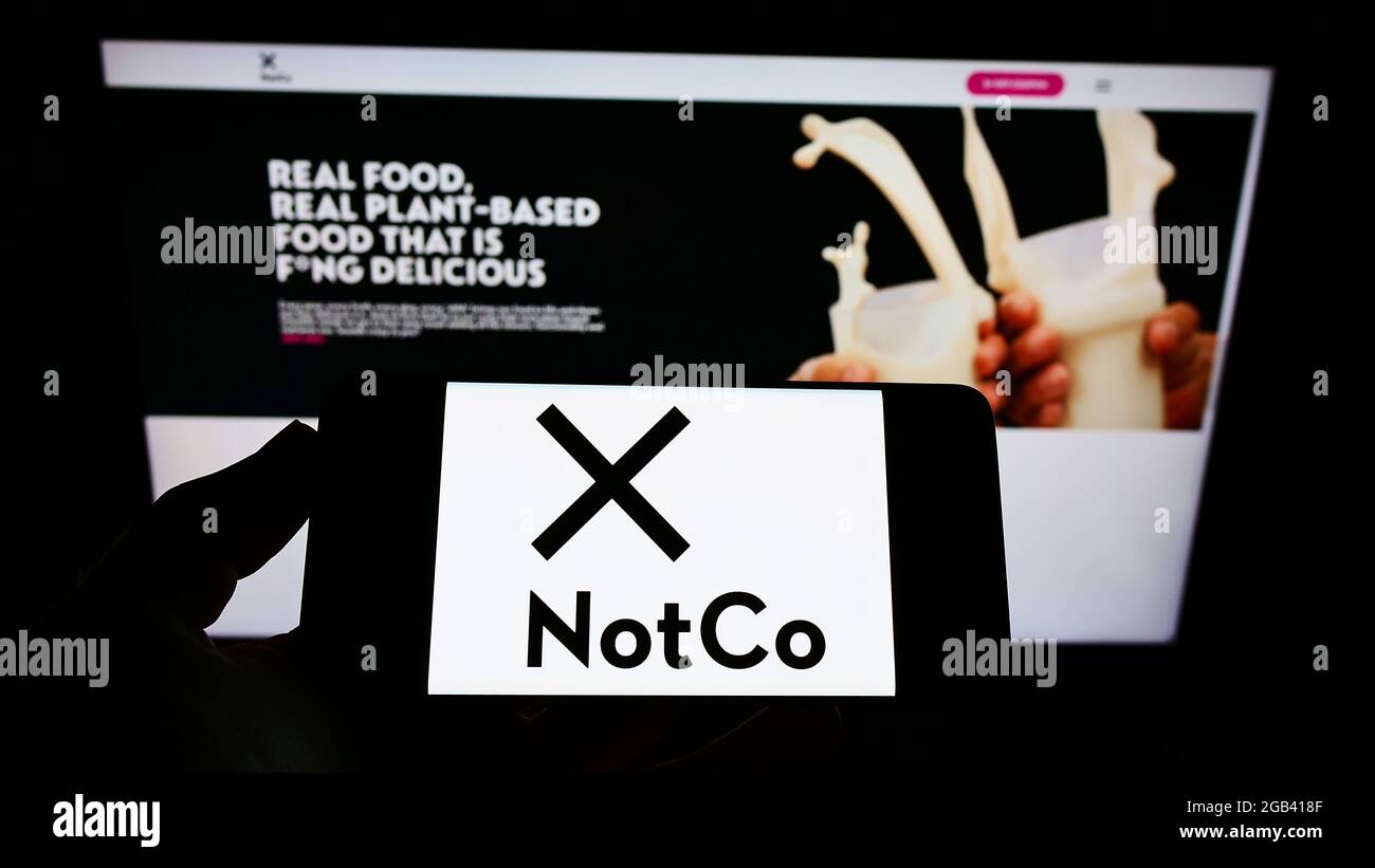 Person mit Mobiltelefon und Logo des chilenischen Lebensmittelunternehmens The Not Company Spa (NotCo) auf dem Bildschirm vor der Webseite. Konzentrieren Sie sich auf die Telefonanzeige. Stockfoto