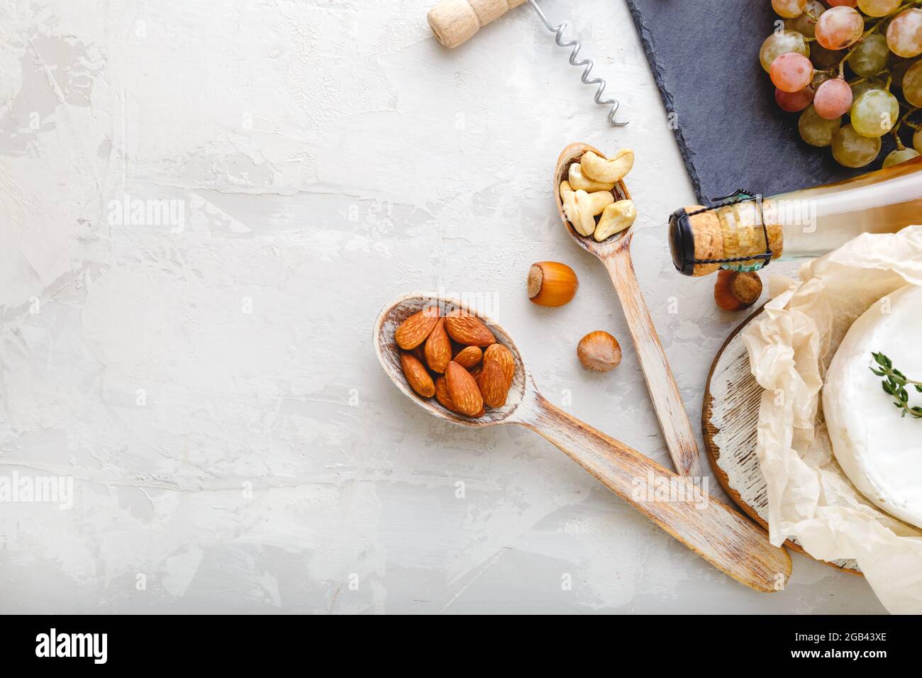 Cashewkerne und Mandelnüsse in Holzlöffeln als Vorspeisen Snack-Set für Wein und Käse auf Stein Hellgrauer Tisch mit Kopierfläche. Rustikale Weinsnacks Stockfoto