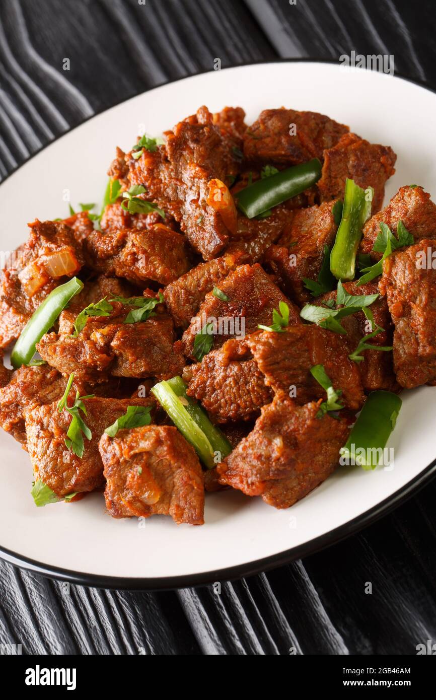 TIBS ist ein beliebtes äthiopisches Gericht aus sautiertem Rindfleisch, gewürzt mit Nitre-Kibbeh und Berbere-Nahaufnahme auf dem Teller auf dem Tisch. Vertikal Stockfoto