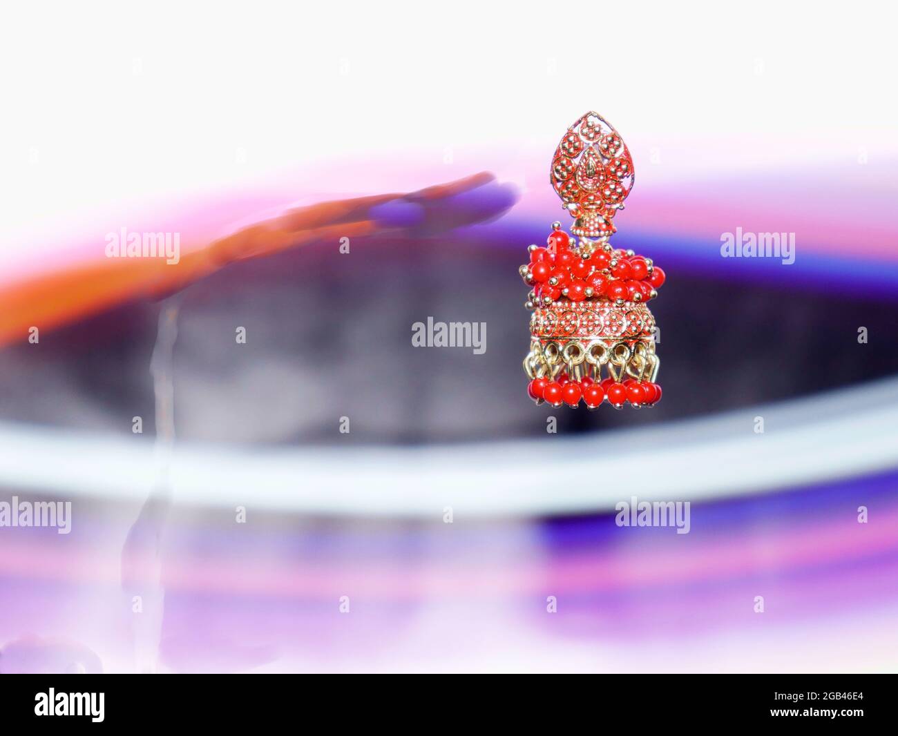 Weibliche rote Farbe Ohrringe an der Luft mit Lichteffekt Glanz Hintergrund präsentiert, Commercial Produkt Präsentation Bild. Stockfoto