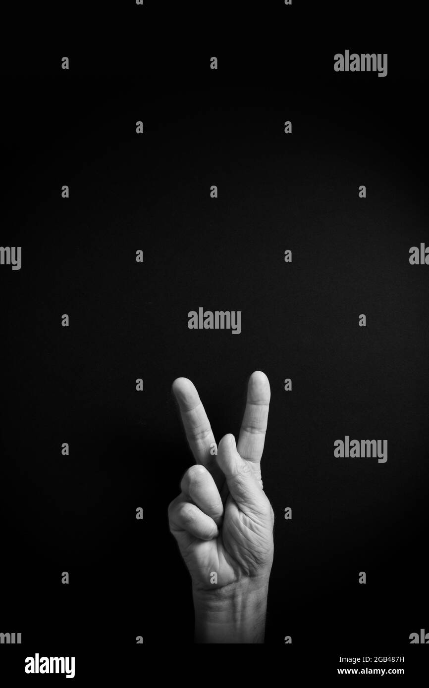 Dramatisches Schwarzweiß-Bild einer männlichen Hand, das den amerikanischen ASL-Zeichennuchenbuchstaben K mit leerem Kopieplatz für Redakteure zeigt Stockfoto