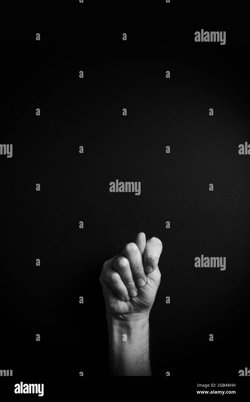 Dramatisches Schwarzweiß-Bild einer männlichen Hand, das den ASL-amerikanischen Zeichennischbrief T mit leerem Kopierraum für Redakteure zeigt Stockfoto