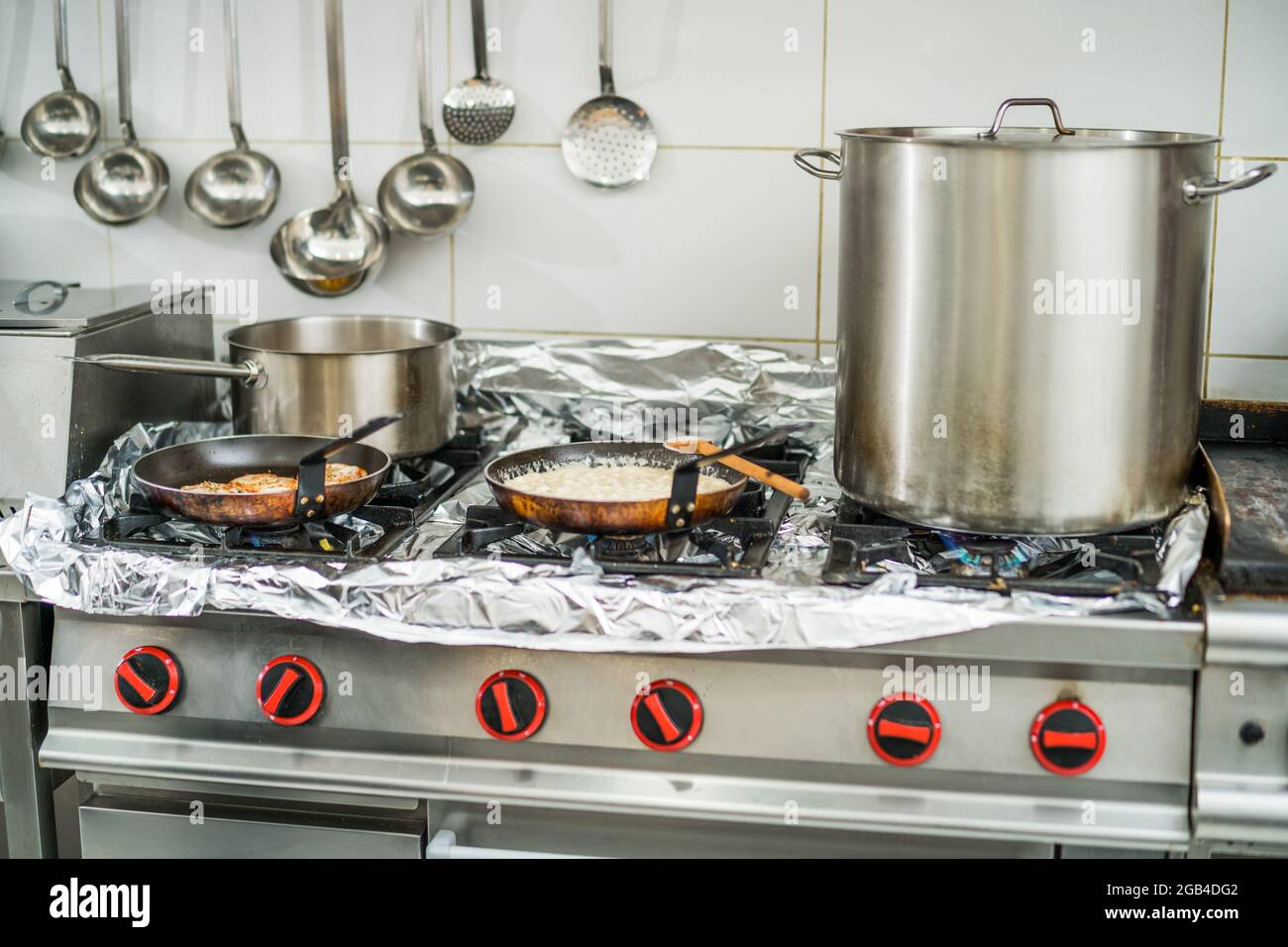 Nahaufnahme des Kochers, während das Fleisch gebraten und die Sauce gekocht wird. Stockfoto