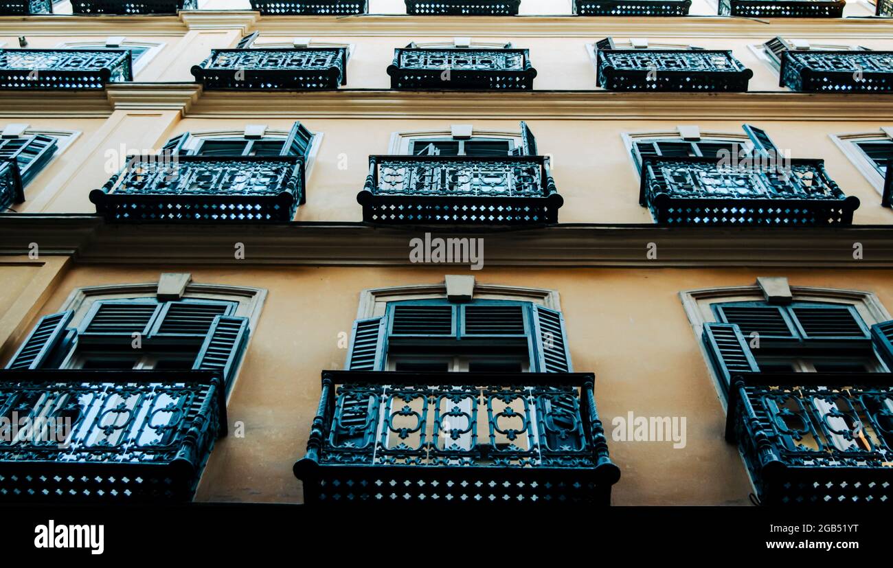 Haus mit französischen typischen Balkonen und Fenstern.Antike Fenster mit schwarzen Lamellen und einem Retro-Look. Architektonisches Detail des Gebäudes. Stockfoto