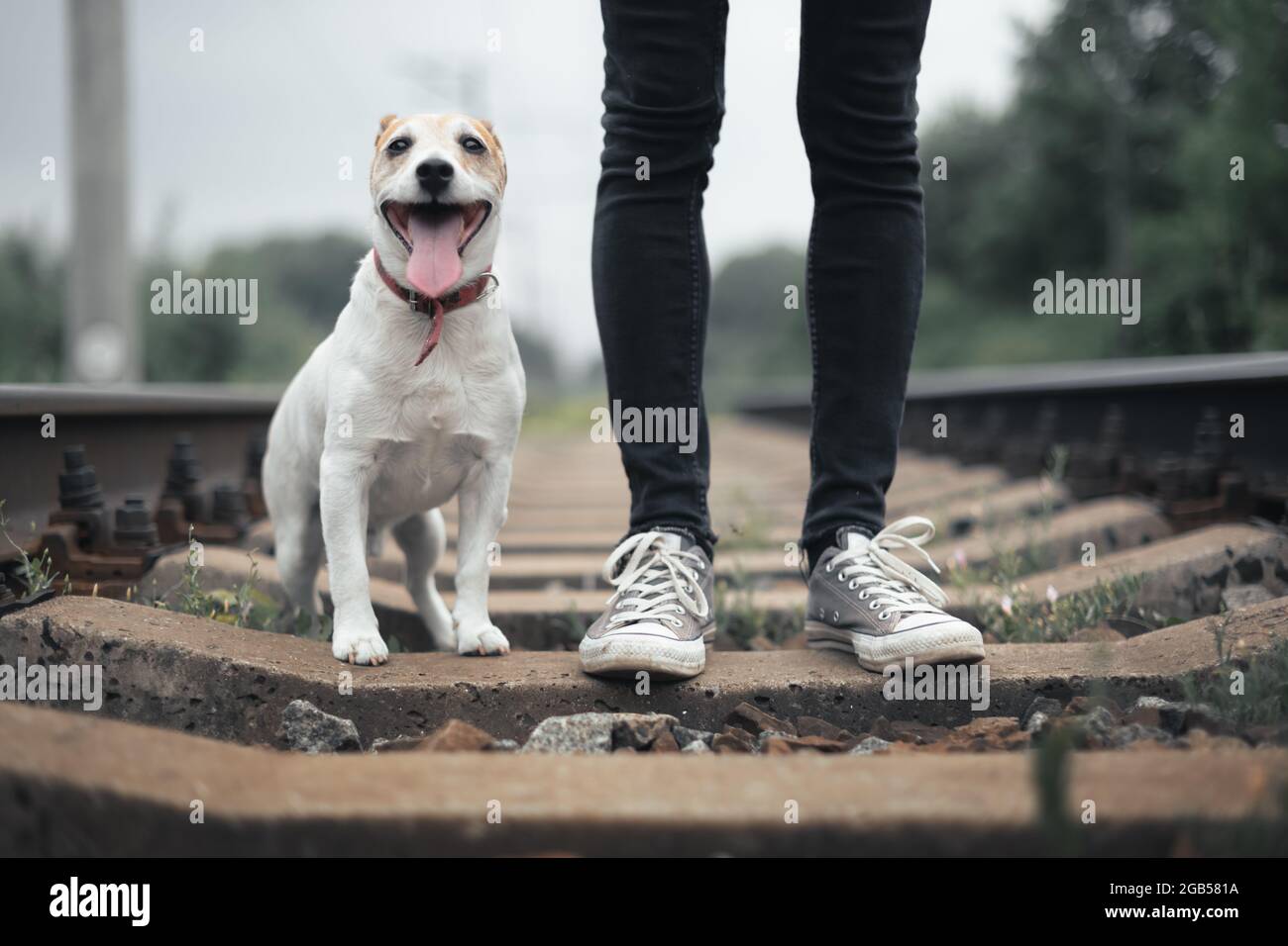 Hipster-Mann in schwarzer Jeans-Hose und grauen Sneakers auf der Bahn Stockfoto