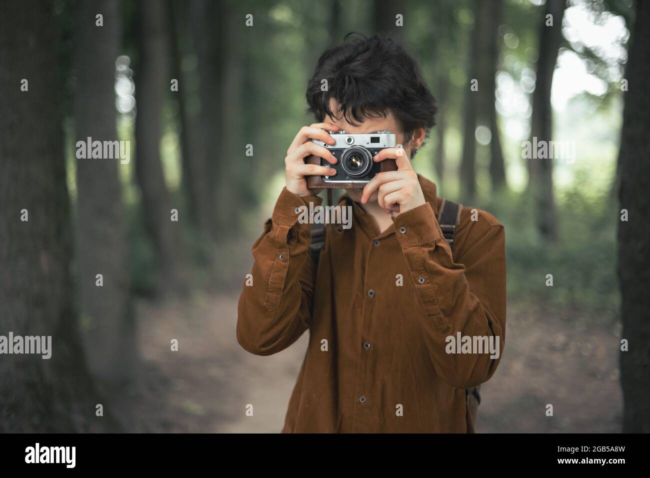 Fotograf in brauner Jacke mit Retro-Kamera im Sommerpark Stockfoto