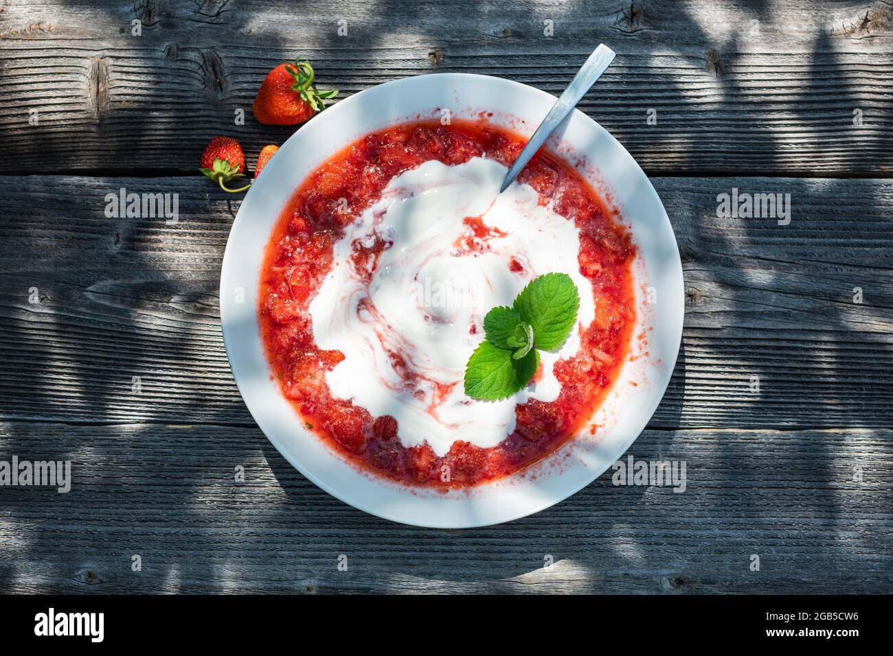 Suppe aus frischen Erdbeerbeeren, Zucker und Sauerrahm mit Minzblatt auf Holztisch Stockfoto