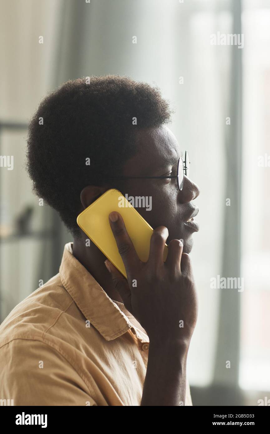 Nahaufnahme eines afrikanischen Mannes in einer Brille, der während seiner Arbeit im Büro auf dem Mobiltelefon sprach Stockfoto