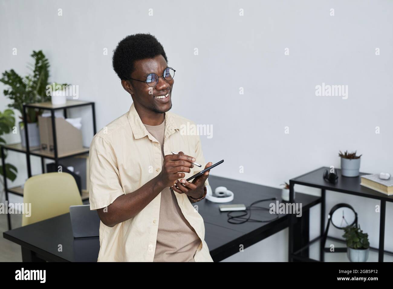 Erfolgreicher afrikanischer Geschäftsmann, der auf einem digitalen Tablet tippt und online arbeitet, während er im Büro sitzt Stockfoto