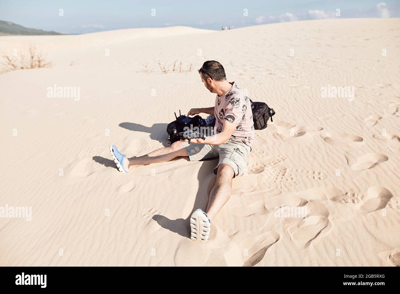 Der Drohnenpilot bereitet sich darauf vor, das Flugzeug auf einer feinen Sanddüne aus der Hand abzuheben Stockfoto