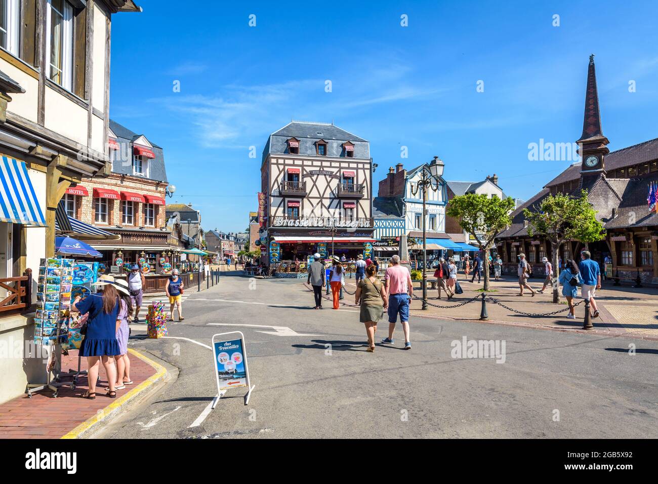 Touristen, die auf dem Marechal Foch Platz in Etretat, Frankreich, flanieren, gesäumt von dem Alten Markt, Fachwerkhäusern, Restaurants, Hotels und Souvenirläden Stockfoto