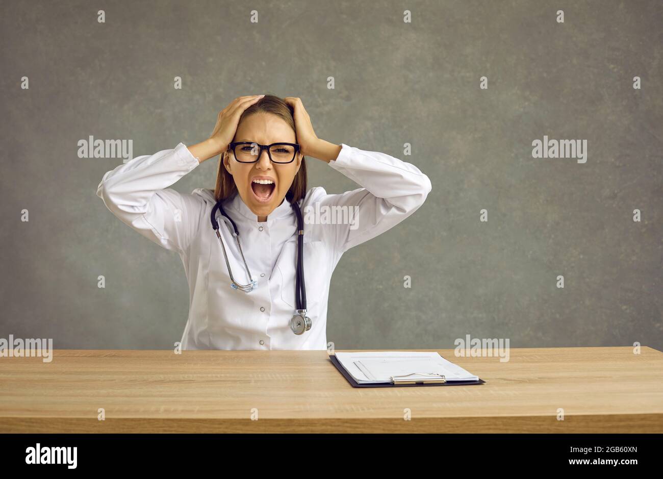Eine Ärztin, die die Gefühle von Frustration und Depression spürt, schreit laut, während sie ihren Kopf hält. Stockfoto