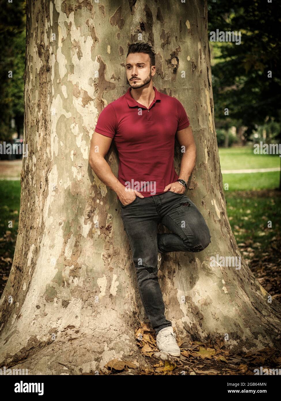 Attraktive junge Mann im Park ausruhen gegen Baum Stockfoto