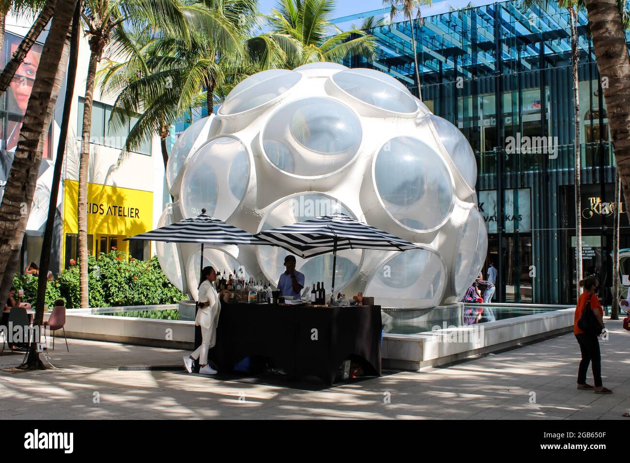 Menschen, die an der Outdoor-Minibar im Miami Design District vor der Fly's Eye Dome-Kunst des Buckminster Fuller Institute vorbei laufen Stockfoto