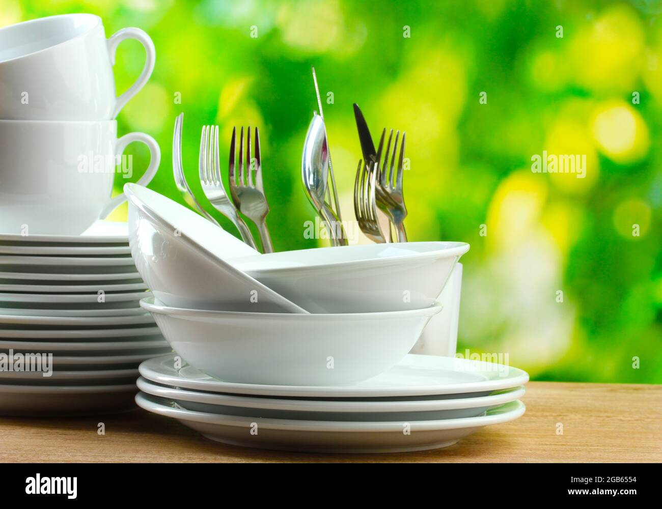 Sauberes Geschirr auf Holztisch auf grünem Hintergrund Stockfotografie -  Alamy