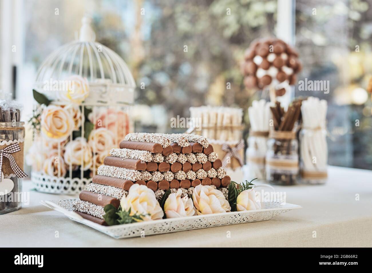 Schwarzer und weißer Schokoladentisch mit handgemachten Pralinen, Cake Pops, Rosen und Dekorationen bei einem eleganten Hochzeitsempfang. Aufnahme mit natürlichem li Stockfoto