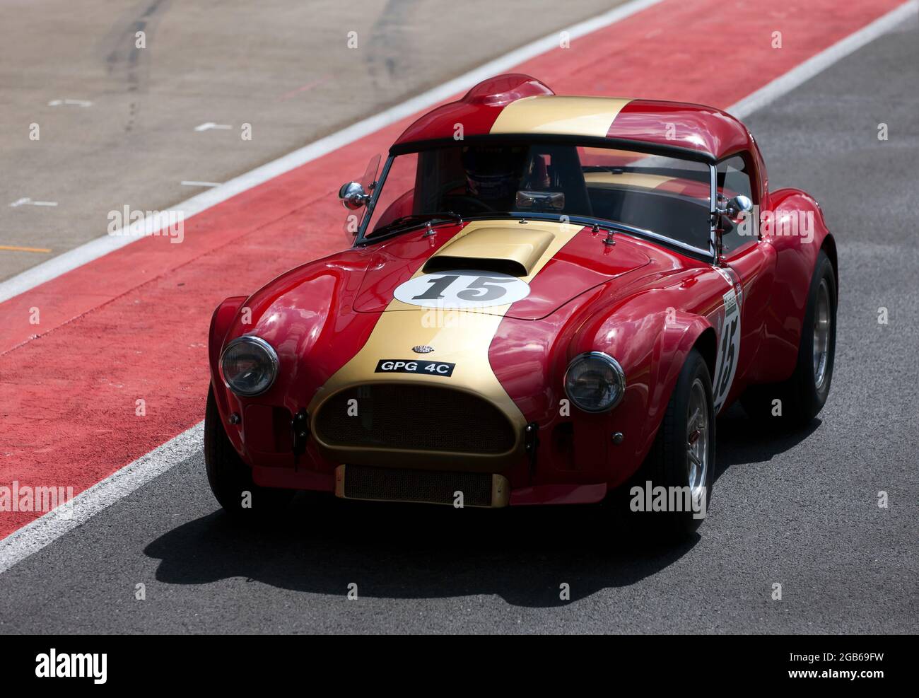 Oliver Bryant fährt mit seinem Red and Gold, 1964, AC Cobra die International Pit Lane entlang, zum Start der International Trophy for Classic Pre-66. Stockfoto