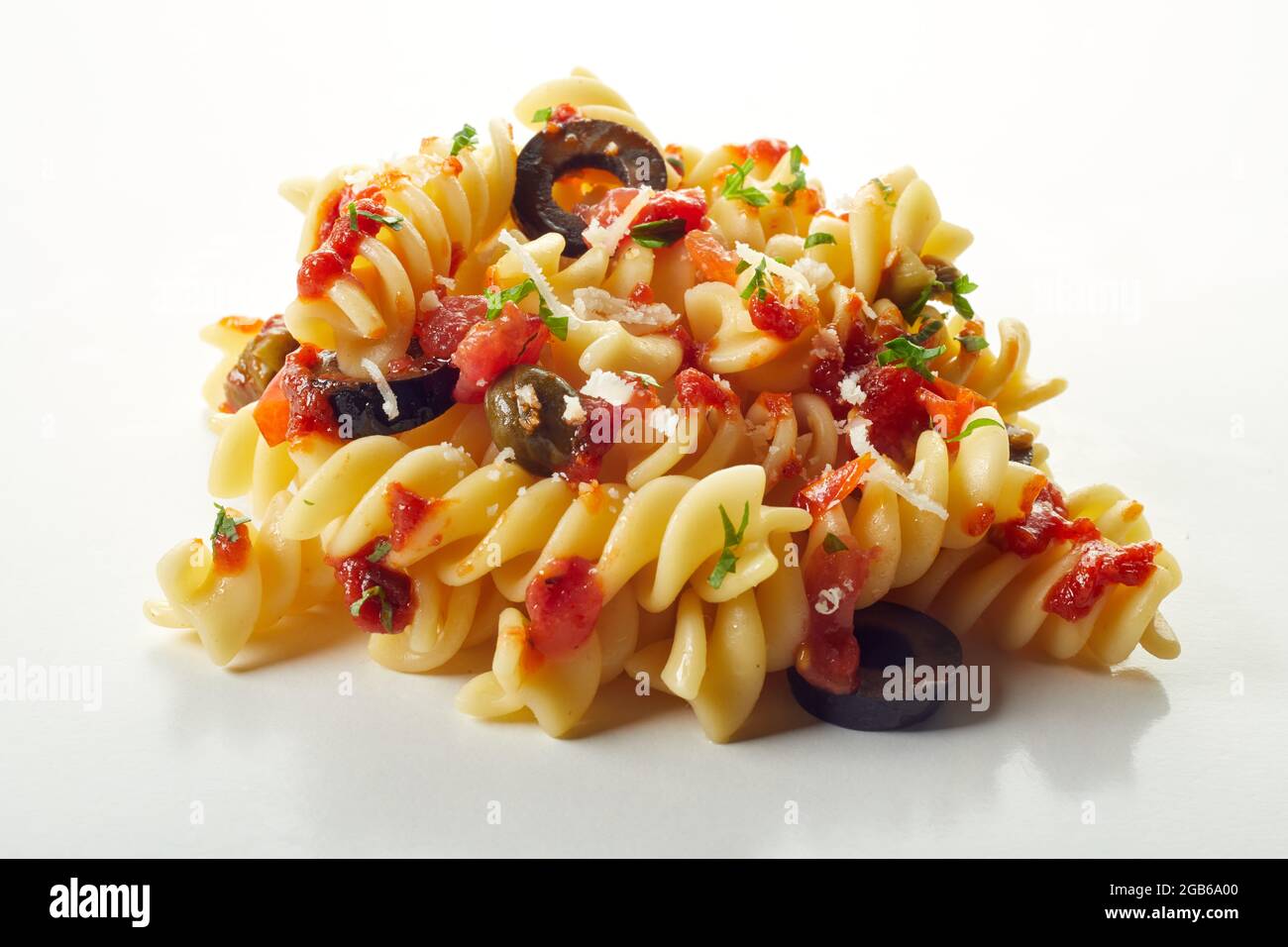 Nahaufnahme Stapel von leckeren Fusilli puttanesca serviert mit Tomatensauce auf weißem Hintergrund Stockfoto