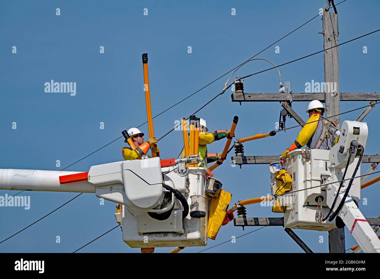 im-rahmen-der-verbesserung-der-infrastruktur-des-rtlichen-stromnetzes-deckt-eine-arbeitsmannschaft-aller-stromversorger-mit-vollem-sicherheitsgeschirr-die-hochspannungsleitungen-ab-um-sich-vor-verletzungen-zu-sch-tzen-da-sie-einen-alten-kurzen-strommast