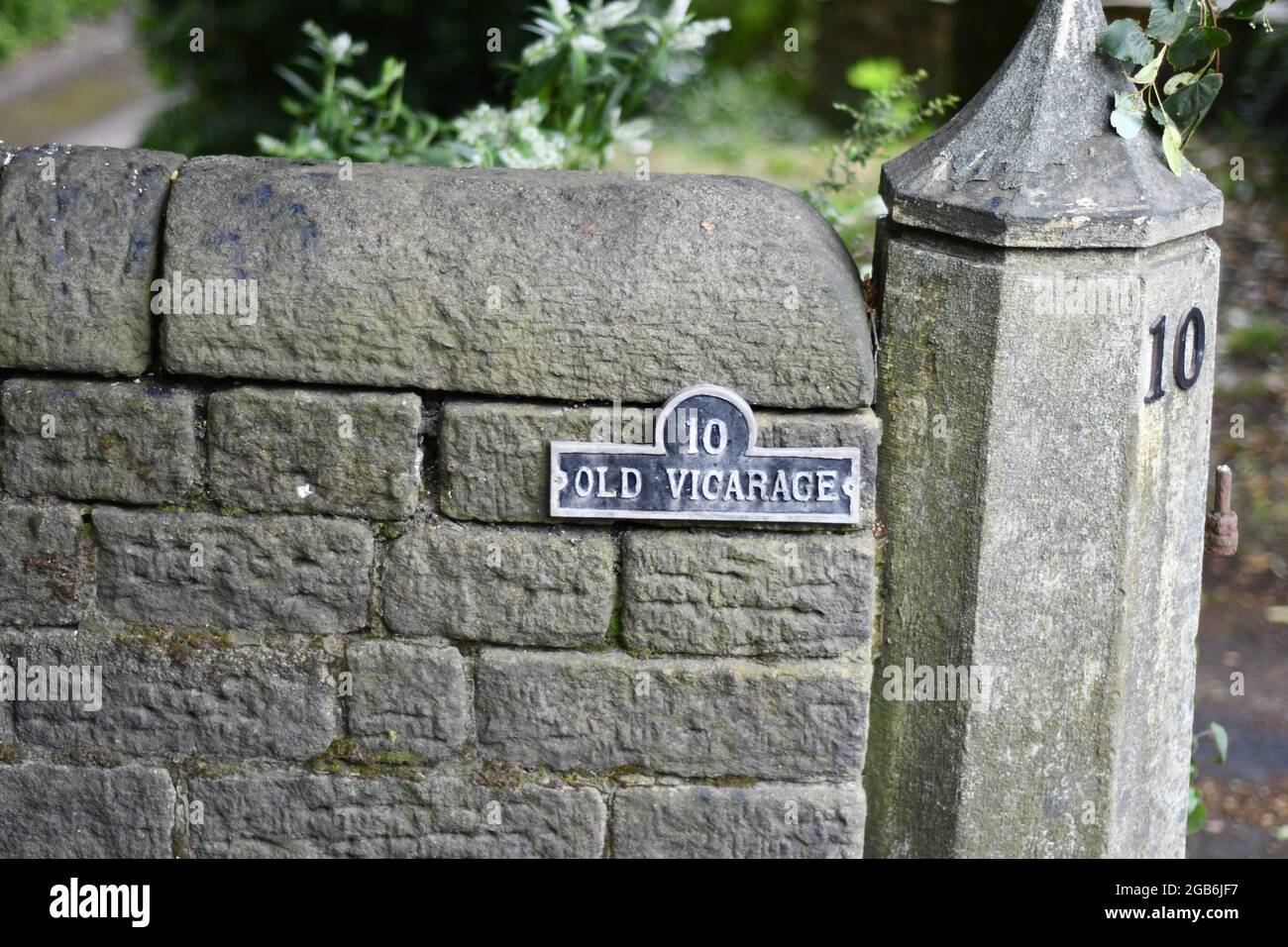 Eine Steinmauer und eine sechseckige Säule aus Stein mit der Hausnummer 10 und dem Titel des Anwesens The Old Vicarage Stockfoto