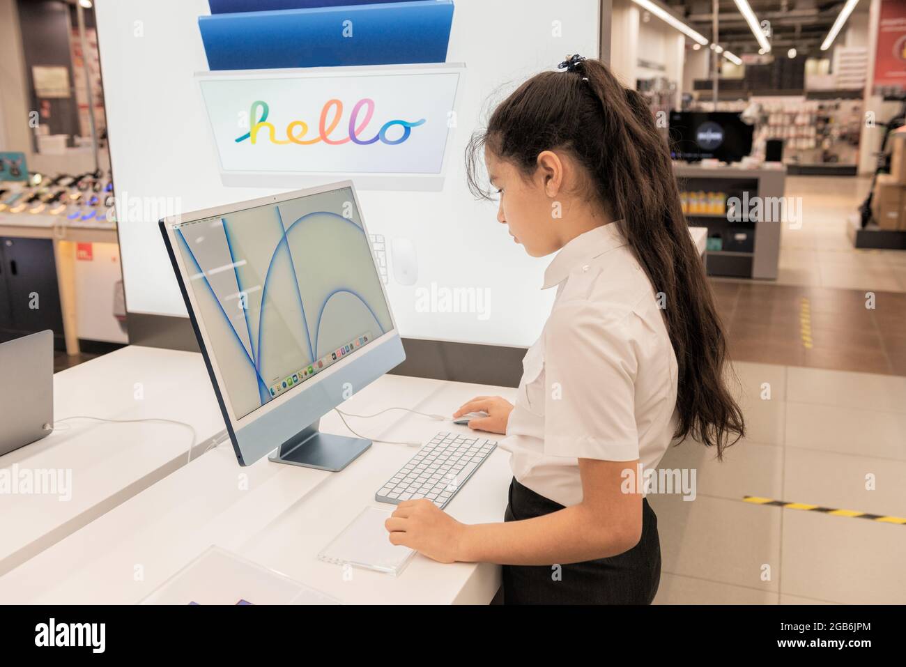 Ein Schulmädchen wählt, überprüft und testet einen Computer in einem Geschäft Stockfoto