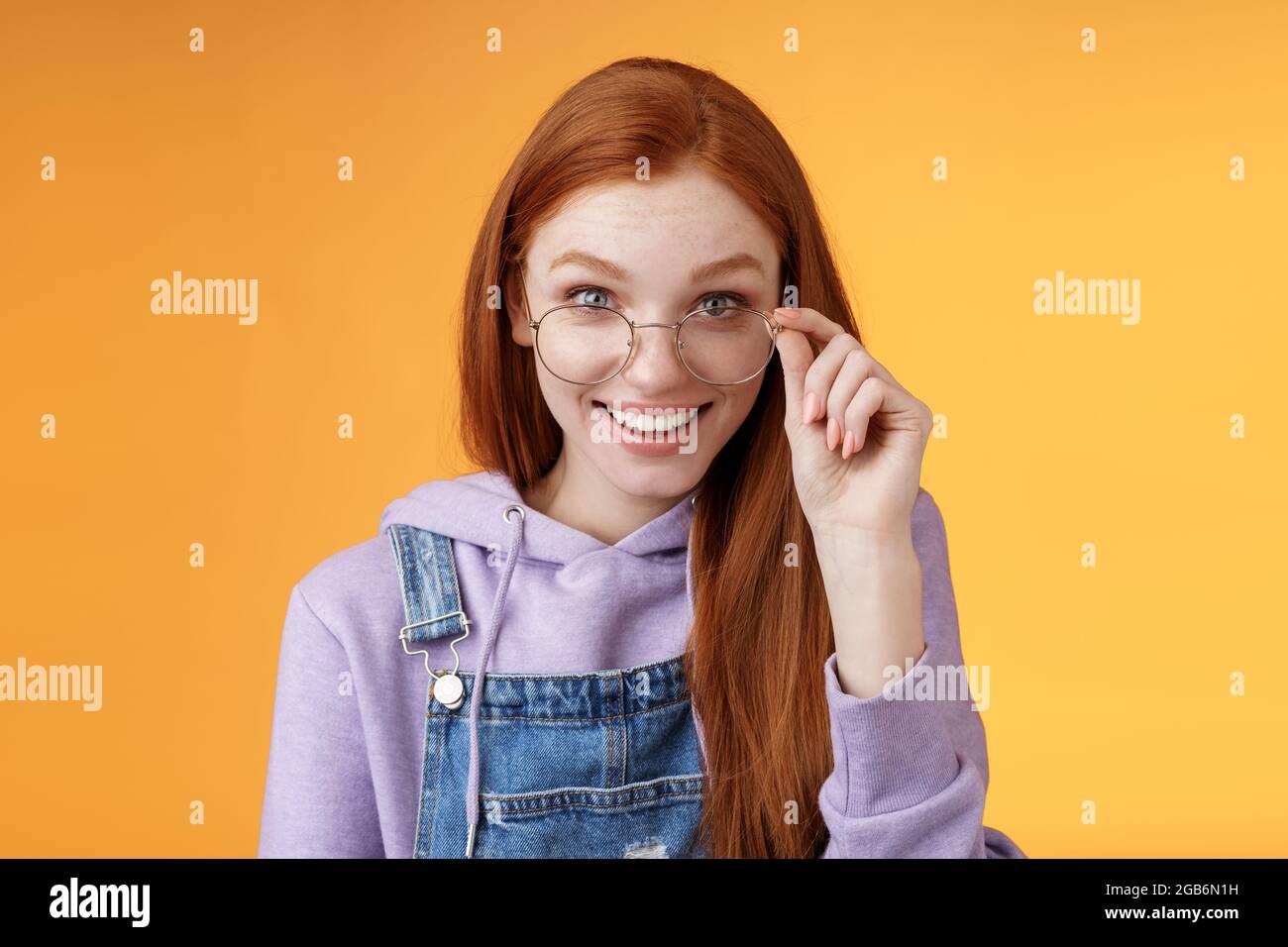 Charming albern bescheiden jungen Rotschopf weibliche Geek Spiel Liebhaber Diskus Die letzten Gaming-Trends lächeln fröhlich amüsiert Touch-Brille grinst neugierig Empfangen Stockfoto
