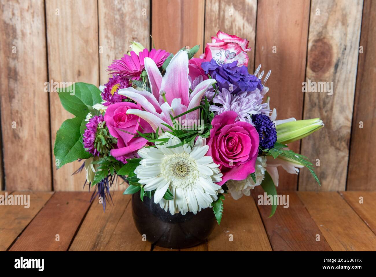 Ein wunderschöner Strauß von Sterngucken, Rosen, Müttern und weißen Gänseblümchen, der in einer schönen Vase präsentiert wird. Stockfoto