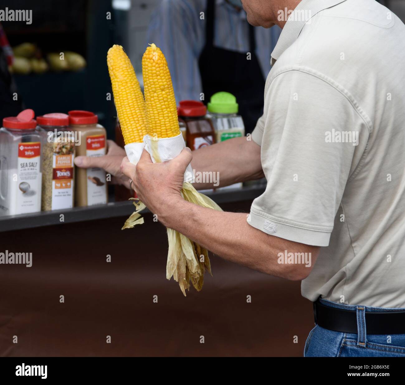 Ein Mann kauft zwei Ähren geröstetem Mais auf dem Cob an einem Lebensmittelstand in Santa Fe, New Mexico. Stockfoto