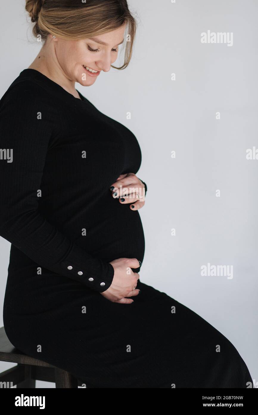 Nahaufnahme Porträt der gogreous schwanger Frau im Bkack Kleid Halten Sie ihre Hand auf dem Bauch und schaut nach unten Stockfoto