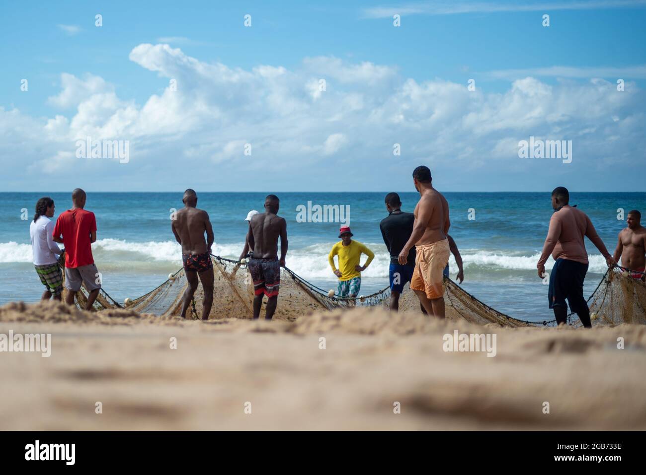 Salvador, Bahia, Brasilien - 23. Mai 2021: Fischer ziehen das Fischernetz aus dem Meer mit Fischen im Inneren. Strand von Boca do Rio in Salvador. Stockfoto