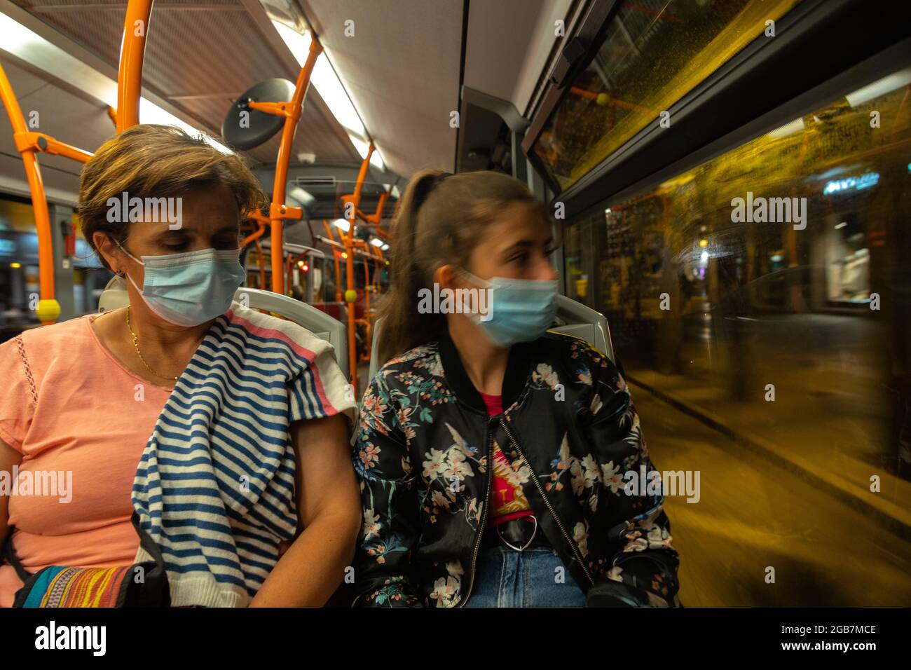 Eine junge Frau mittleren Alters sitzt mit Maske im Bus 19, während sie mit selektivem Fokus durch den Stadtkonzept-Verkehr fährt Stockfoto