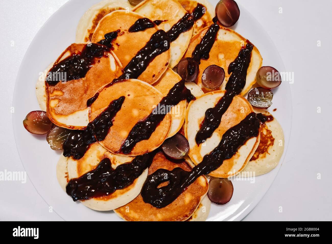 Hausgemachte glutenfreie Pfannkuchen mit Schokoladensauce auf einem weißen Teller. Stockfoto